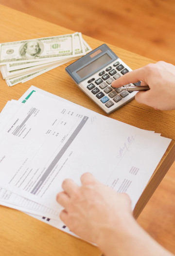 A person comparing documents and contents while using a calculator